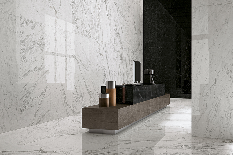 Marvel Pro Statuario Select tile installed on floors and partial walls and columns with Noir St. Laurent installed on walls and front desk slab in office lobby