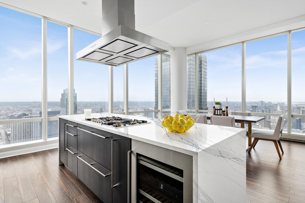 Modern city penthouse with floor to ceiling city views. Two toned cabinets with luxury appliances. White Gray and Stainless Steel.