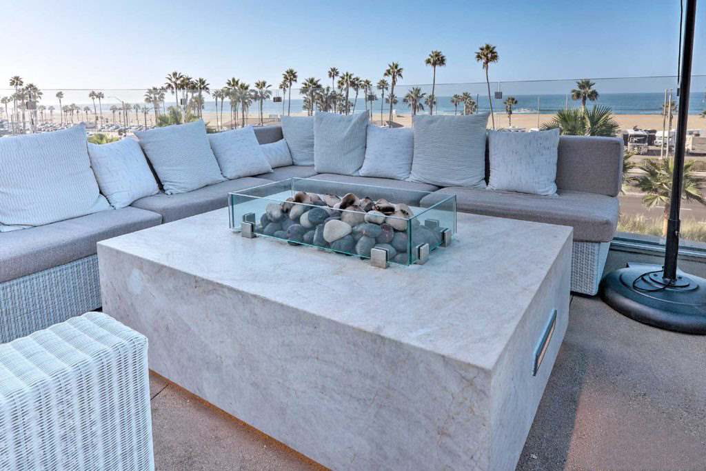 Rooftop patio with a Taj Mahal quartzite fire table overlooking the ocean